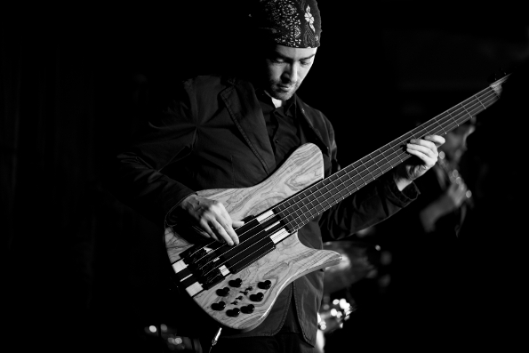Photo of Andrew Bruhelius, bass player for the band Prince Ali-X and his Ambassadors, credited to Peter Graham, design by Musicos Productions